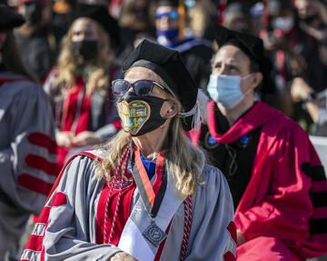 graduate wearing regalia and a mask