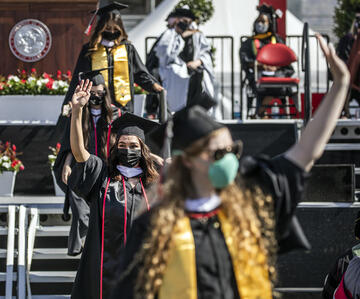 graduates with masks waving