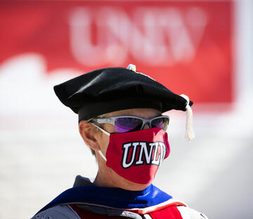 male graduate with regalia wearing mask