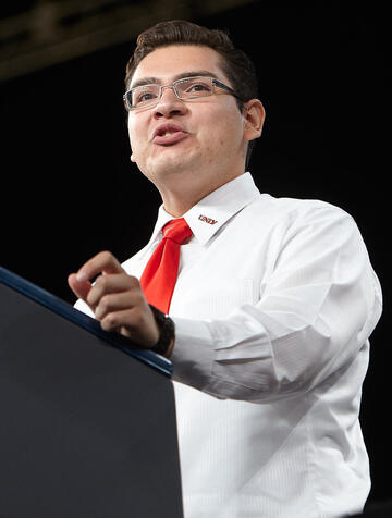 Front-side view of a man standing at the podium in mid-speech.