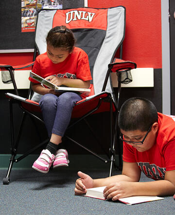 Two younger children focused and reading books.