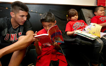 Student helping out three younger children who are focused on their books.