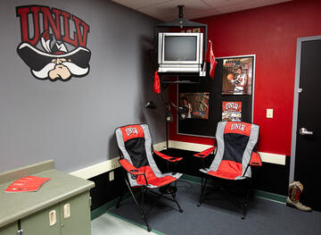 Reading room with tv in corner and iconic UNLV logo on wall.