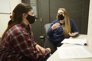 two women, wearing face masks for safety, talking