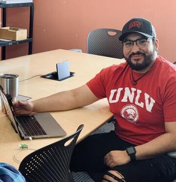 man in UNLV T-shirt at computer