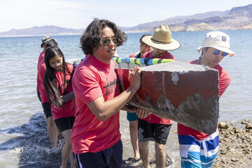 UNLV students carrying concrete canoe out of lake