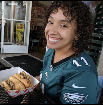 Jessica Carr smiles while wearing a football teal jersey. 