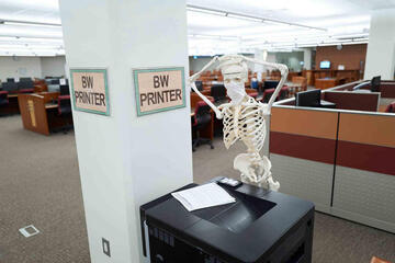 Skeleton standing in front of printer