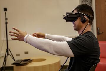 male nursing student using VR googles with arms raised in front of him