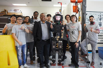 Santiago Ricoy (right) joins President Keith E. Whitfield and the robotics team next to Avatar-Hubo, a humanoid robot they created for the ANA XPRIZE competition. (Becca Schwartz)