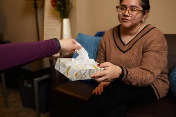 a young woman offers a client a box of tissues