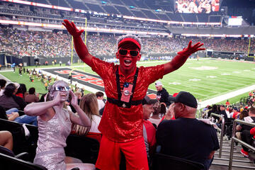 Lester Cruz dressed head-to-toe in red glitter hypes up the crowd during a football game