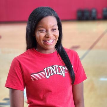 Jaslin Short smiles in front of camera while wearing a red UNLV shirt.