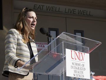 woman speaking at podium with UNLV School of Integrated Health Sciences sign