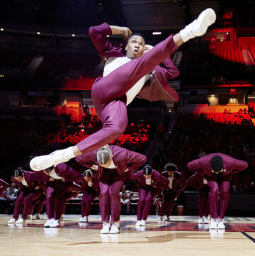 male dancer leaping in front of group of hip hop dancers