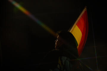 face in shadow with PRIDE flag in background