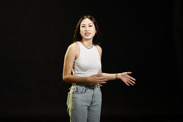 Woman in a white tank top in front of a black background
