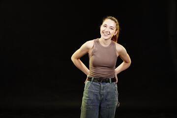 Woman in a brown tank top in front of a black background