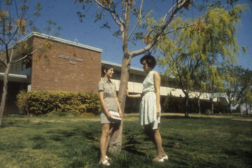 Late 1960s photo of building exterior with two students standing in front