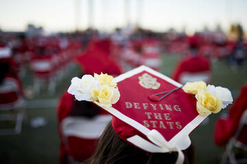 decorated commencement cap saying "Defying the Stats"