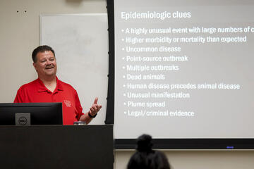 Man teaching with presentation slide titled "Epidemiologic clues"