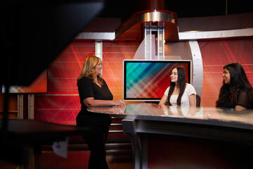 two female students and female lecturer on TV news set