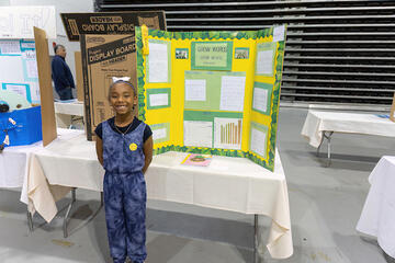 student standing in front of science project display