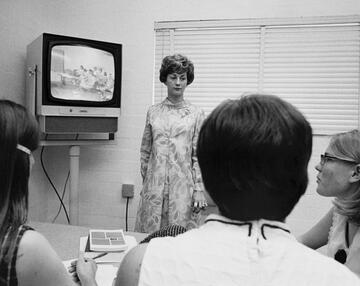 black and white photo of 3 people watching TV screen