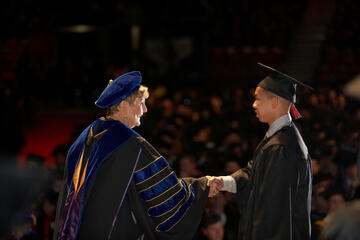 woman and man shaking hands on graduation stage