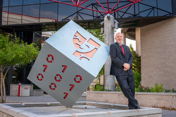 man leaning on cubed sculpture in front of building