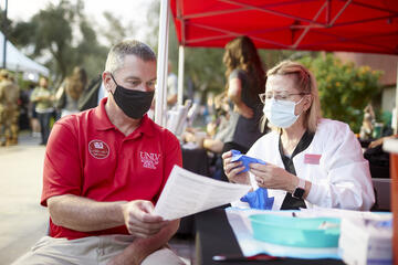 Two people wearing masks at an outdoor vaccine station.