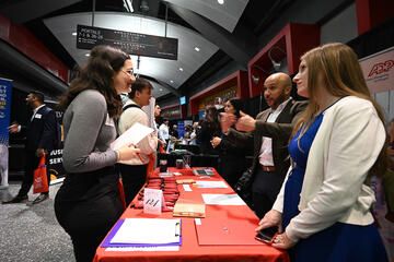 individuals speaking across a table at a career fair booth