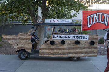 A golf cart decorated like a pirate ship waving a UNLV flag