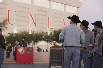 three men in cowboy hats outside building with UNLV sign
