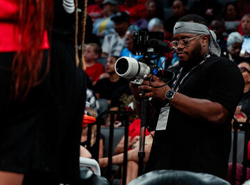 man holding camera at basketball game