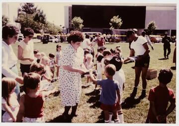 woman interacting outside with group of children