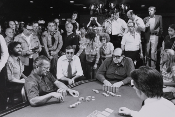 crowd gathered around players at poker table