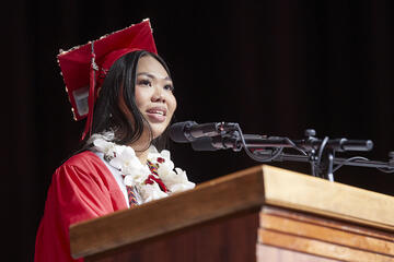 woman in graduation regalia speaking