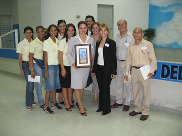 group of people posing while one woman in front holds framed plaque