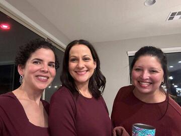 three women wearing burgundy shirts and smiling