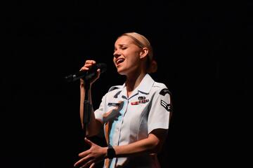 woman in uniform singing at a mic