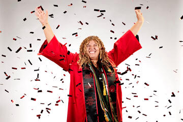 Ashley McCoy wearing a red cap and gown as confetti falls