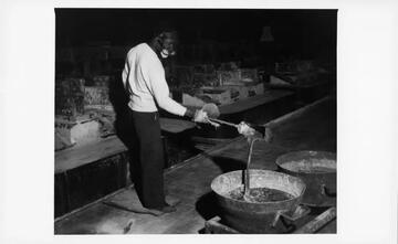 African American man shoveling liquid magnesium at factory