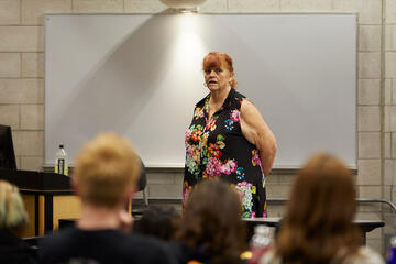 woman speaks at front of a room full of people during workshop