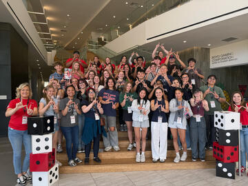large group of high school students gather on staircase in hospitality building