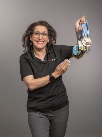 Anjala Krishen holding medals attached to ribbons