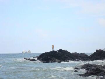 David Cardenas in the background on a rock in ocean near Ayampe, Ecuador