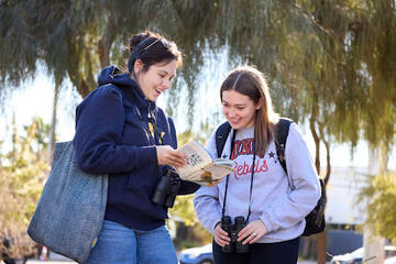 two female birding club members look at their guidebook