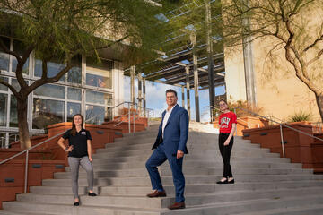 White man in a royal blue suit and white collared shirt stands on steps outside of a UNLV building with his two daughters flanking him on both sides