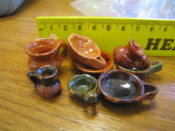 small pieces of colorfully glazed pottery being measured by a ruler
